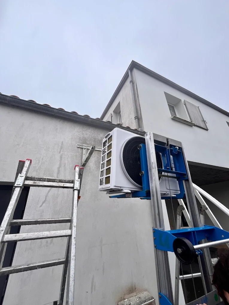 Groupe extérieur de climatisation hissé au lève-charge et fixé en façade d'une maison