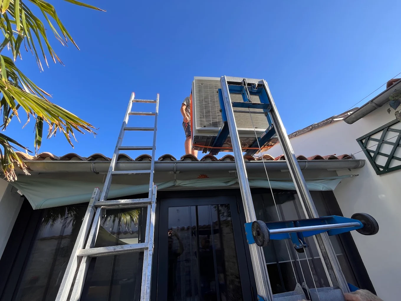 Groupe extérieur de climatisation monté sur une toiture en tuiles à l'aide d'un lève-charge
