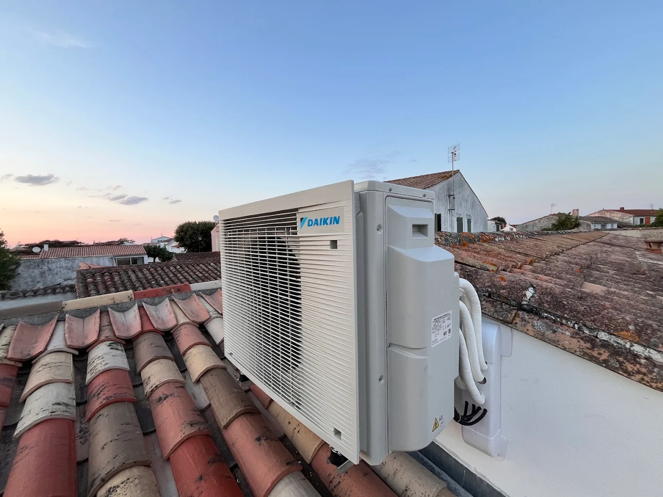 Groupe extérieur de climatisation Daikin posé sur une toiture en tuiles, chantier Artisans du Perthuis