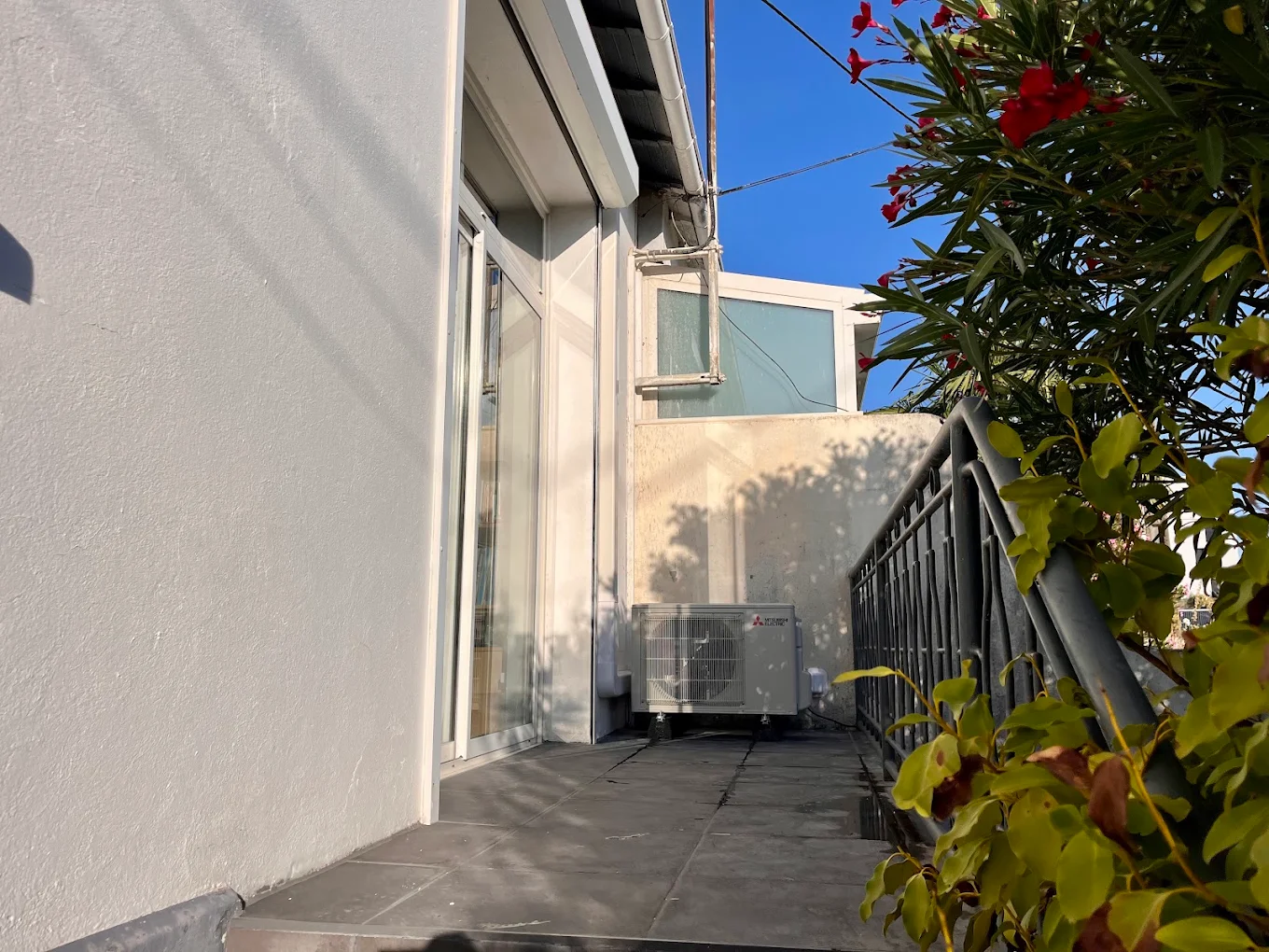 Groupe extérieur Mitsubishi Electric installé sur une terrasse le long d'une baie vitrée
