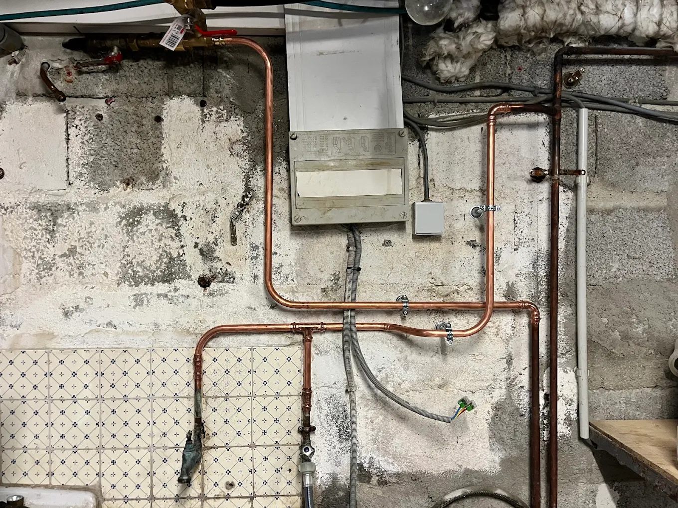 Réseau de distribution en cuivre neuf et chauffe-eau gaz instantané dans un sous-sol en pierre